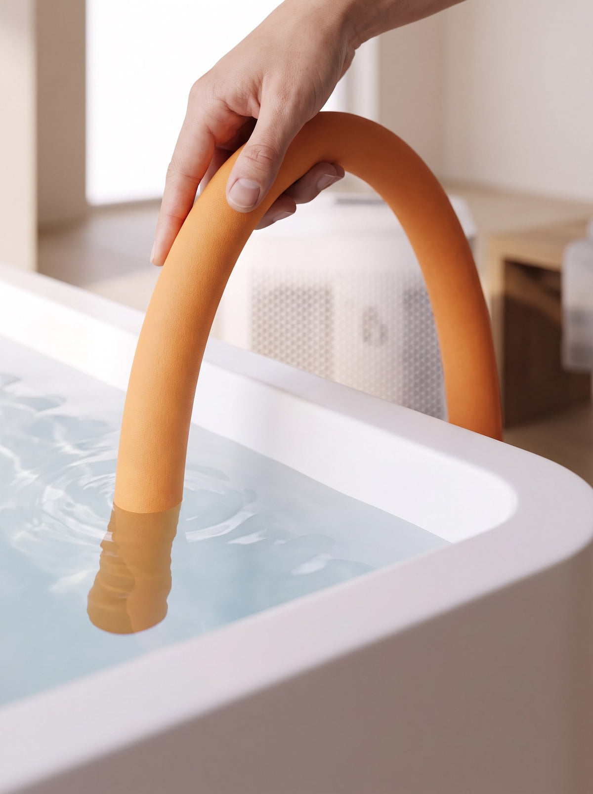 Norge N-03: a hand lowering the insulated hose over the rim of a white bath into the water